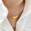 Dettaglio del ciondolo a cuore dorato su una sottile catena a serpente indossata al collo - Cuore Oro