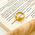 Detailed close-up of a U-shaped gold plated titanium steel ring on a vintage book page - Modern Gold U-shaped Open Style