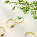 Dettaglio di anelli placcati in oro 18K con zirconi verdi e ciondolo a croce nera - US 6 / Zirconia Rettangolare Verde