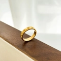 Dettaglio dell'anello in acciaio dorato con incisioni a stella su vassoio di legno - US 6 / Stelle incise / Oro