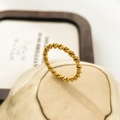 Macro-opname van een minimalistische 18K vergulde gedraaide ring op een keramische houder - US 6 / Dubbellaagse Grove Twist