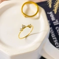 Dettaglio dell'anello d'oro con tre zirconi bianchi scintillanti in una montatura elegante - Stile piccoli zirconi