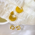 Vista macro de pendientes geométricos dorados y elegantes ear cuffs con perlas finas - Pendientes de aro con recorte geométrico en abanico