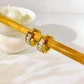 Detalle de pendientes de aro dorados con circonitas rectangulares sobre madera - Pendientes huggie con circonita cuadrada