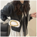 Detail der weißen ovalen Clutch mit goldenem Rundgriff und schlankem Kettenriemen - Weiß