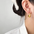 Detalle de un pendiente de gota minimalista chapado en oro de 18K puesto en la oreja - Media luna / Dorado