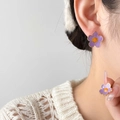 Détail de puce d'oreille fleur violette avec cœur orange sur mannequin en pull blanc - Style de Fleur Violette (Grand)