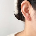 Gros plan de boucles d'oreilles minimalistes en or avec deux zircons clairs portées - Style Zircon Rond