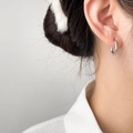 Close-up of minimalist silver geometric earring worn on model, sleek polished steel finish - Steel Color Hollow Oval Style
