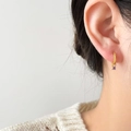 Detailed close-up of a gold hoop earring with a lavender zircon pendant on a model - Mini Purple Zirconia