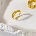 Détail d'une bague croisée plaquée or 18 carats sur un support en pierre blanche - Deux lignes croisées fermées