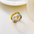 Dettaglio di anelli intrecciati in acciaio inossidabile oro e argento su fondo di porcellana - US 6 / Stile Sovrapposto Cavo a 2 Strati