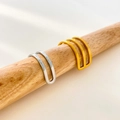 Detail of minimalist gold and silver rectangular open rings on light wooden display - US 6 / Two-color Interlocking Split Ring
