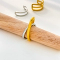 Close-up of interlocking gold and silver rings on a wooden stand in a minimalist design - US 6 / Two-color Spliced Curve Open