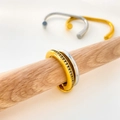 Close-up of dual-tone titanium steel interlocking rings with crystal pavé and wood prop - US 6 / Two-color Double Ring With Zirconia