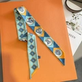 Close-up of a geometric animal print twilly silk scarf draped over an orange box - 8*95cm / Aqua