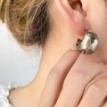 Close-up of a large chunky silver dome hoop earring with a polished mirror finish - Hollow Thick Moon / Steel