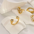 Detail eines 18K vergoldeten Sternrings mit Zirkonia auf weißer Steinstruktur - US 6 / Doppel Fünfzackiger Stern Zirkonia Offen