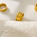 Macro detail of three 18K gold plated titanium steel rings with geometric textures - US 6 / Three Arcs