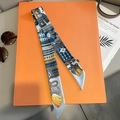 Nahaufnahme von Seidentwilly-Schal mit blauem Rüstungsdruck auf orangefarbener Box - Himmelblau