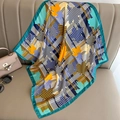 Detail of silk square scarf featuring houndstooth and maple leaf patterns on a beige sofa - 70*70cm / Aqua Green