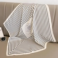Foulard quadrato in seta con motivo a camelia e bordo su divano in pelle grigia - Righe Bianco