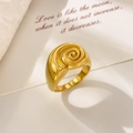 Macro shot of 18K gold plated titanium steel spiral ring on a white quote card - Snail