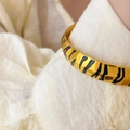 Detail of 18K gold-plated titanium leopard print bangle featuring black enamel textures - Tiger Print