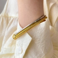 Close-up of dual-layer gold and silver bracelets with cubic zirconia on a linen cuff - Double Ring Circle Zirconia