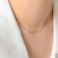 Dettaglio di una collana in acciaio al titanio dorato con delicati ciondoli in zircone - Stile Stazione a Sette Zirconi