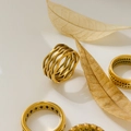 Dettaglio di anelli in titanio placcati oro 18K con motivi geometrici traforati e intrecci - US 6 / Rete a Onde Traforata