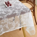 Détail d'une nappe en dentelle blanche avec motifs floraux vintage sur table en bois - 150x150cm / Blanc