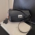 Glossy black underarm bag with silver buckle and leather charm in a lifestyle setting - Black
