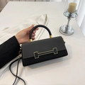 Black fashionable box bag with woven texture and gold buckle in a minimalist setting - Black