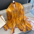 Elegant floral silk scarf in orange and gold with dark borders on a stylish sofa - 135x190cm / Orange Floral (B-101-Orange)