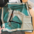Silk scarf with emerald and cream geometric horse head pattern on a display board - 70cmx70cm / Dark Green