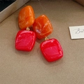 Close-up of geometric resin earrings with orange and red marble texture on velvet - Orange & Red Color Block