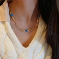 Elegante collar de cuentas doradas con esferas de piedra azul usado por una modelo - Collar de Cuentas de Turquesa Azul (C448)