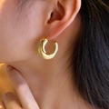Close-up of matte brushed gold C-shaped curved earrings worn on model for a minimalist look - Brushed Crescent (E1580) / Gold