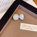 Detailed close-up of irregular baroque style pearl earrings on a premium display tray - Gold