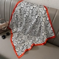 Eleganter Seidenschal mit schwarz-weißem Rosenmuster und rotem Kontrastrand auf dem Sofa - Roter Rand