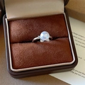 Detailansicht eines Stern-Zirkonia-Rings mit weißer Perle in einer Schmuckschatulle - Kätzchen Perle Offener Ring Stil (K102)