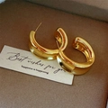 Detalle de pendientes de aro dorados en forma de C sobre terciopelo con tarjeta regalo - Aro Liso Ancho Irregular (E2228) / Oro Mate