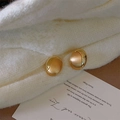 Dettaglio di orecchini ovali dorati con finitura spazzolata opaca e lucida su maglia - Oro Spazzolato - Ovale Diviso