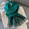 Close-up of green silk blend scarf with gold stripes and mesh trim on beige knit - Green