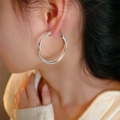 Silver interlocking hoop earrings with matte and polished texture on female model - Large Frosted Cross (E2750) / Silver