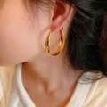 Luxe matte gold-plated crisscross hoop earrings with faceted shimmering texture on model - Large Frosted Cross (E2750) / Gold