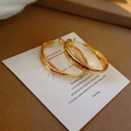 Close-up of gold layered hoop earrings with frosted texture and polished finish on a card - Small Frosted Cross (E2751) / Gold