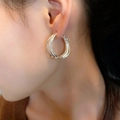 Close-up of silver layered hoop earring with matte textured finish on female model ear - Wavy Hoop Earring (E0435) / Silver