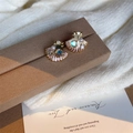 Golden seashell earrings with iridescent pearl and zircon details on a soft display - Pink Shell